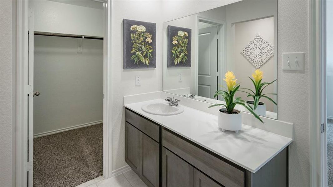 Bathroom with vanity, light carpet, a spacious closet, and a textured wall