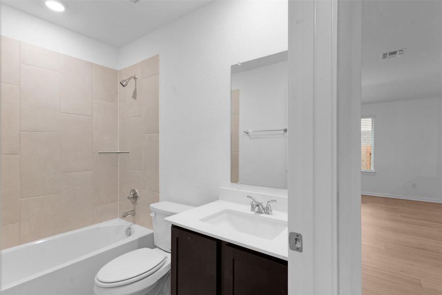 Bathroom featuring vanity, tub / shower combination, wood finished floors, and recessed lighting