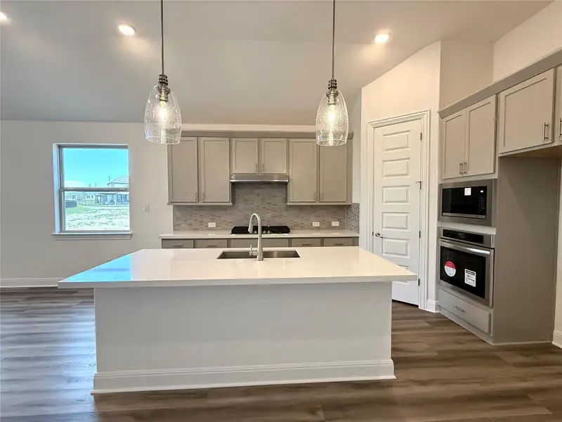 Kitchen with stainless steel appliances, vaulted ceiling, gray cabinetry, a sink, and decorative backsplash Kitchen with stainless steel appliances, vaulted ceiling, gray cabinetry, a sink, and decorative backsplash