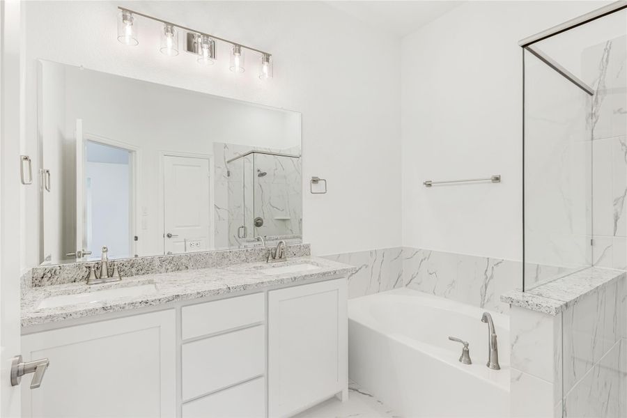 Master bathroom with double vanity, granite countertops, soaking tub, and glass shower with marble tile surround Master bathroom with double vanity, granite countertops, soaking tub, and glass shower with marble tile surround