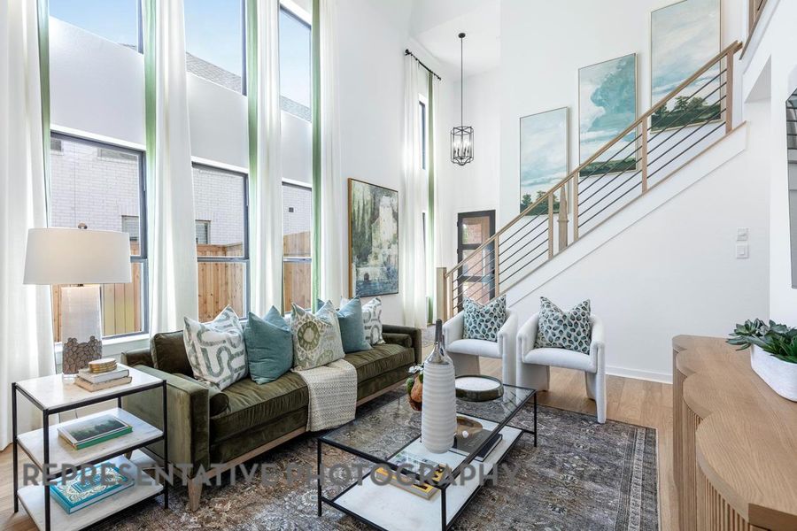 Living area with healthy amount of natural light, a high ceiling, stairway, and wood finished floors Living area with healthy amount of natural light, a high ceiling, stairway, and wood finished floors