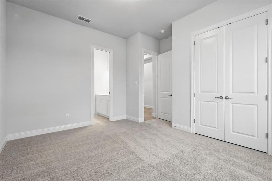 Unfurnished bedroom featuring light colored carpet, baseboards, and ensuite bathroom Unfurnished bedroom featuring light colored carpet, baseboards, and ensuite bathroom