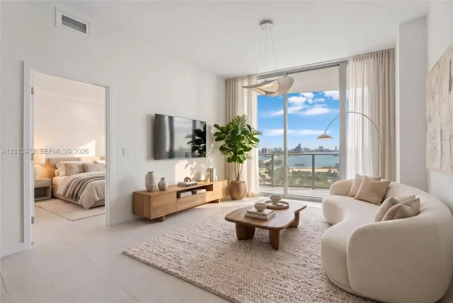Floor-to-ceiling sliding glass doors, porcelain tile flooring, sculptural ceiling pendant lighting, and a private balcony featuring a water backdrop. VIRTUALLY STAGED
