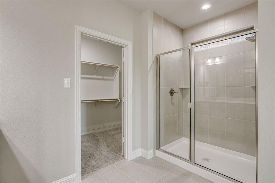 Full bath featuring a walk in closet, a stall shower, light tile patterned floors, and recessed lighting Full bath featuring a walk in closet, a stall shower, light tile patterned floors, and recessed lighting