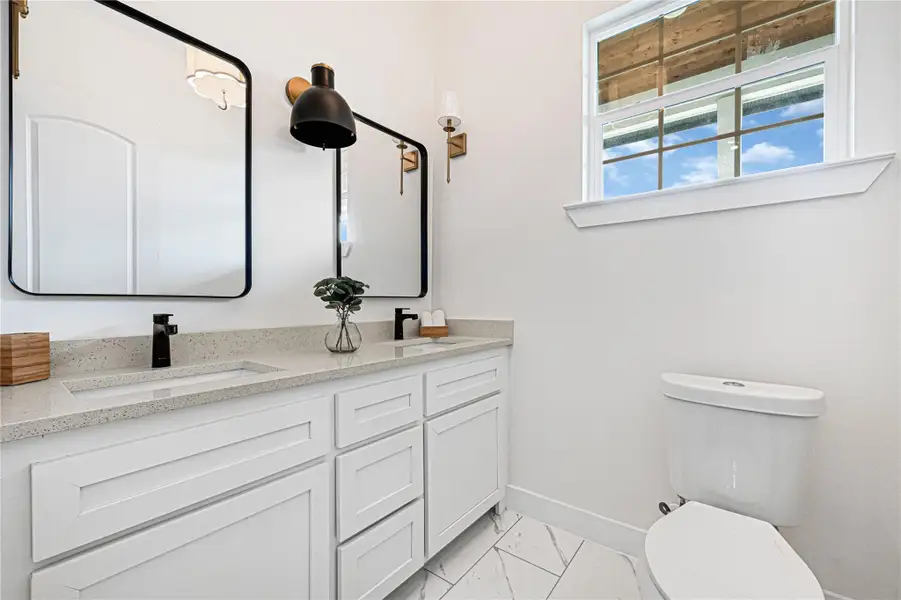 Stylish half bath with modern fixtures, ample natural light, and sleek design.