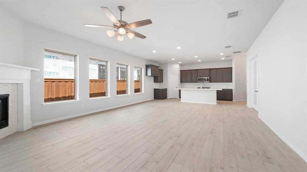 Unfurnished living room with light wood-type flooring, ceiling fan, a fireplace, and sink