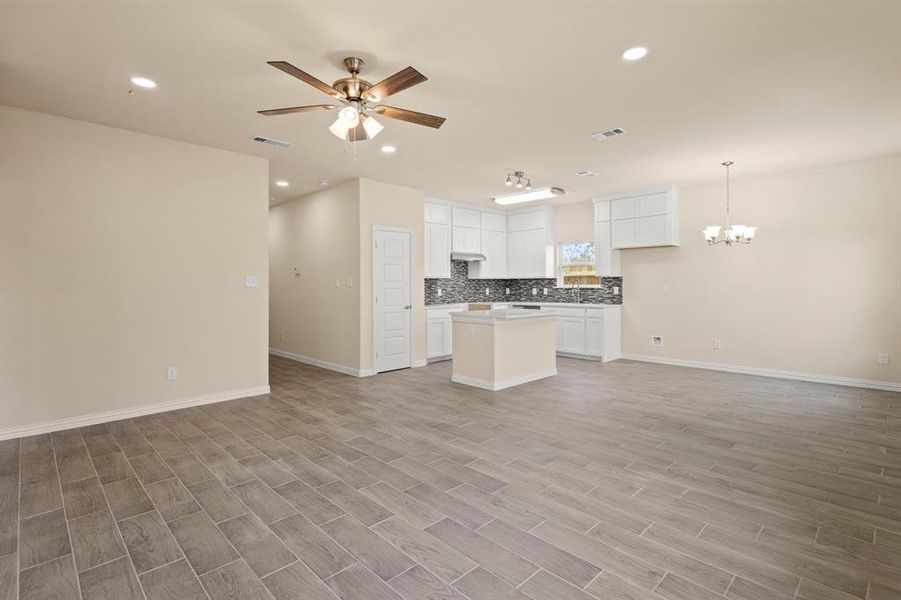 Kitchen featuring open floor plan, tasteful backsplash, ceiling fan with notable chandelier, and visible vents