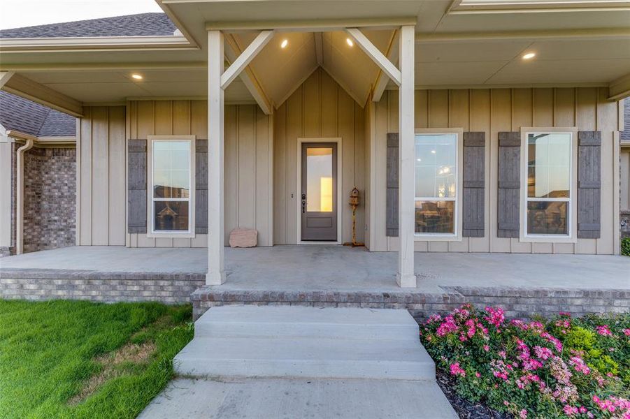 Entrance to property featuring a shingled roof and covered porch