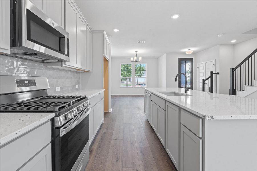 Kitchen featuring appliances with stainless steel finishes, dark wood-type flooring, a chandelier, tasteful backsplash, and recessed lighting
