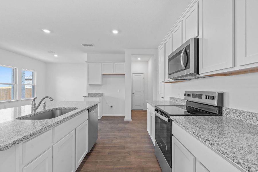 Kitchen featuring stainless steel appliances, white cabinetry, recessed lighting, light stone countertops, and dark wood finished floors Kitchen featuring stainless steel appliances, white cabinetry, recessed lighting, light stone countertops, and dark wood finished floors
