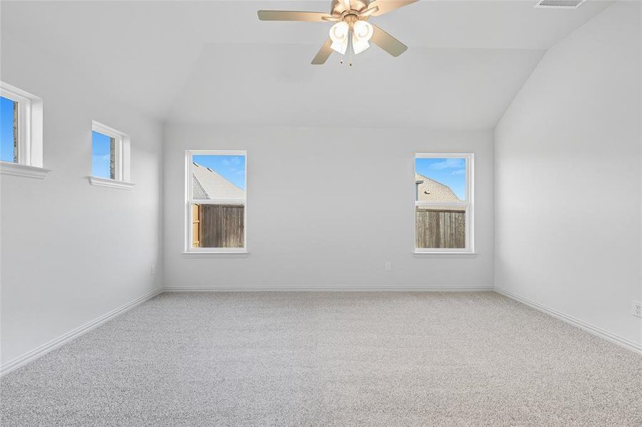 Unfurnished room with carpet flooring, ceiling fan, and vaulted ceiling Unfurnished room with carpet flooring, ceiling fan, and vaulted ceiling