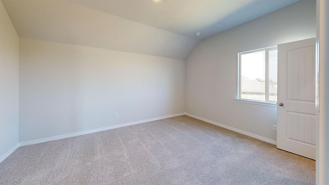 Bonus room featuring vaulted ceiling and light colored carpet Bonus room featuring vaulted ceiling and light colored carpet