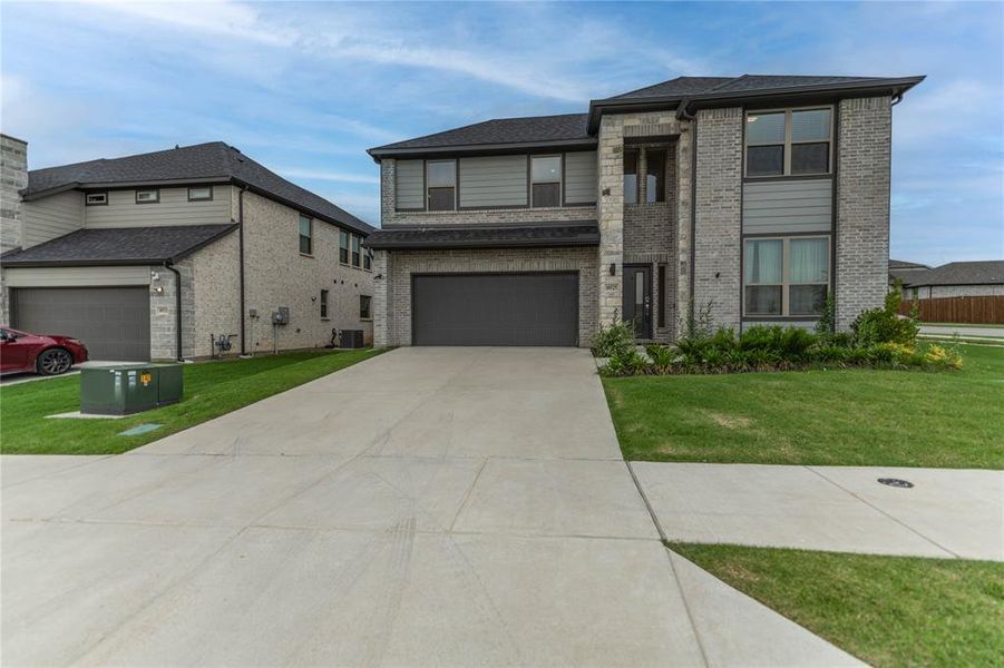 Prairie-style house with brick siding, a front lawn, concrete driveway, and cooling unit