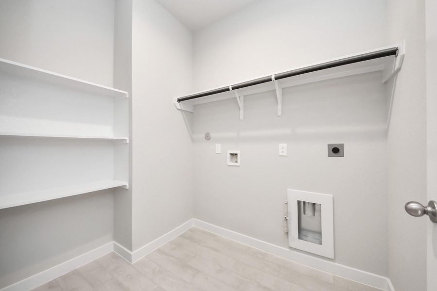 A perfect blend of functionality and comfort. Capture the essence of easy living with a first-floor laundry room, thoughtfully equipped with shelving for effortless organization. Both electric and gas connections available. Sample photo of completed home with similar floor plan. Actual colors and selections may vary.