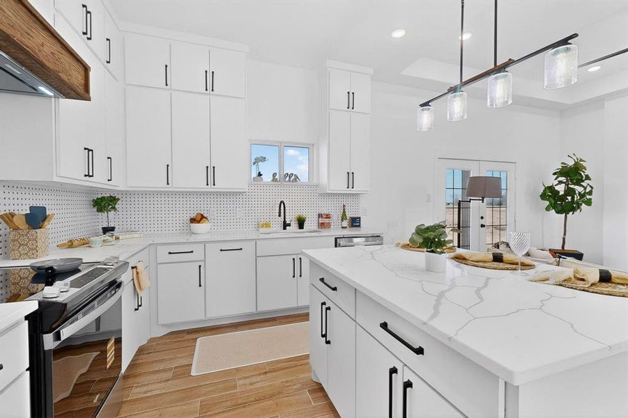 Kitchen with white cabinets, light stone countertops, pendant lighting, a center island, and premium range hood