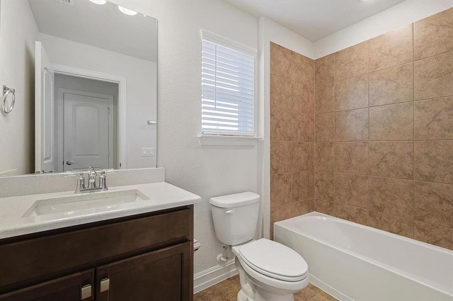 Full bathroom with tile patterned floors, washtub / shower combination, vanity, and toilet