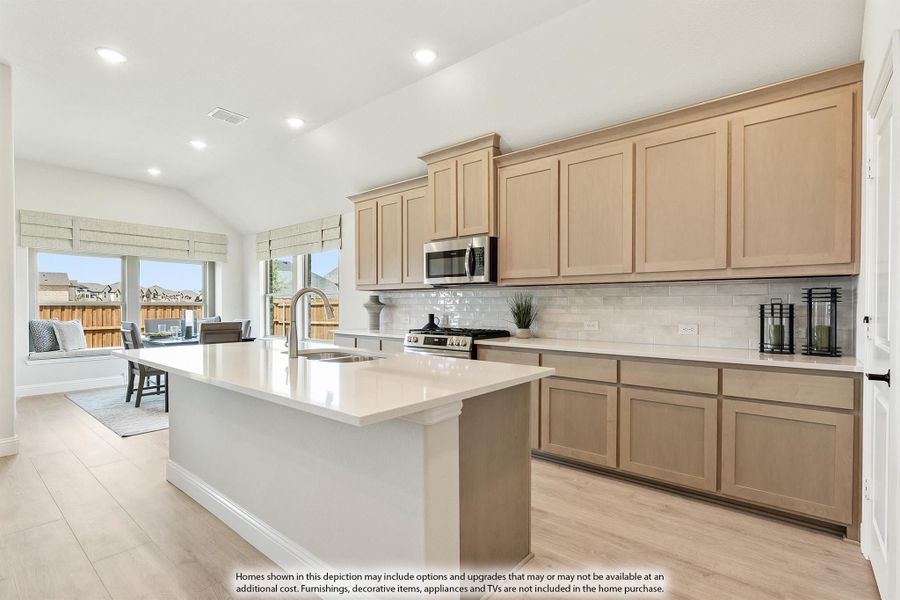 Kitchen with large center island, light wood cabinets, white tile backsplash, and stainless steel appliances