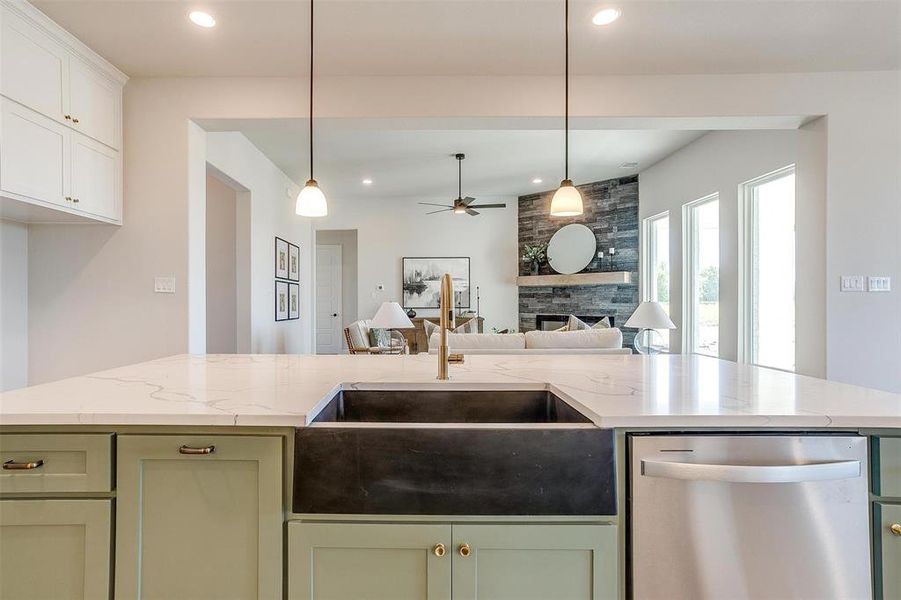 Kitchen with dishwasher, light stone counters, a fireplace, and ceiling fan