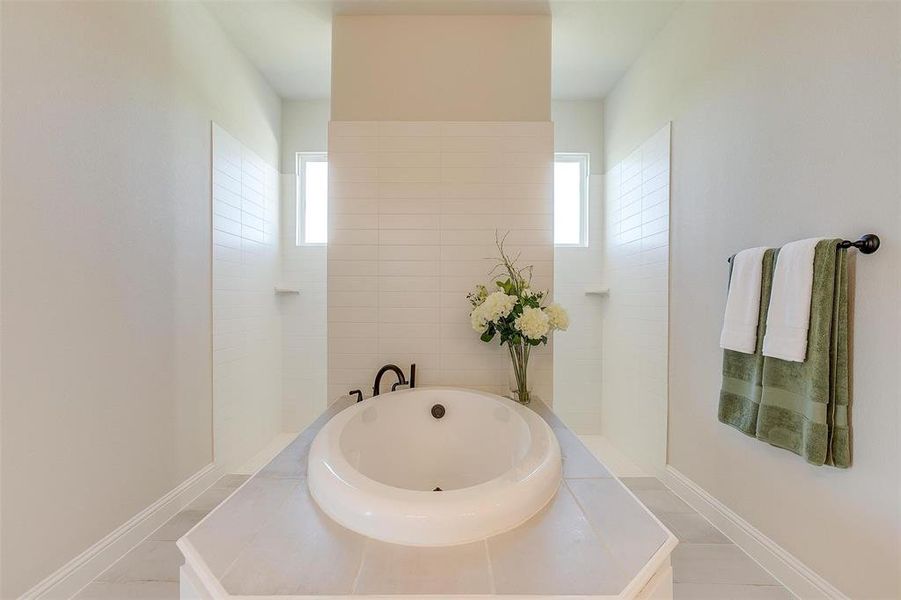 Bathroom with tile patterned floors, a bathtub, and a wealth of natural light