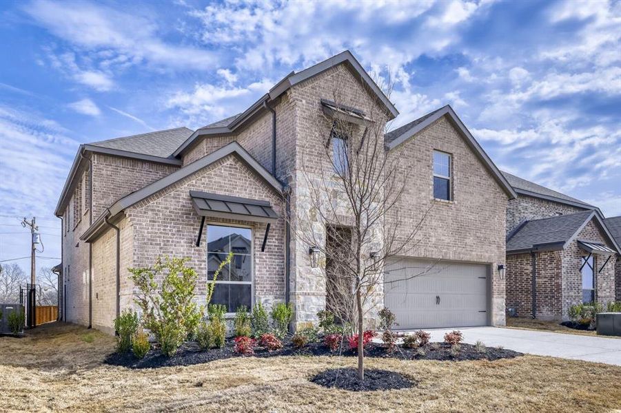 French provincial home with brick siding, a garage, concrete driveway, stone siding, and roof with shingles