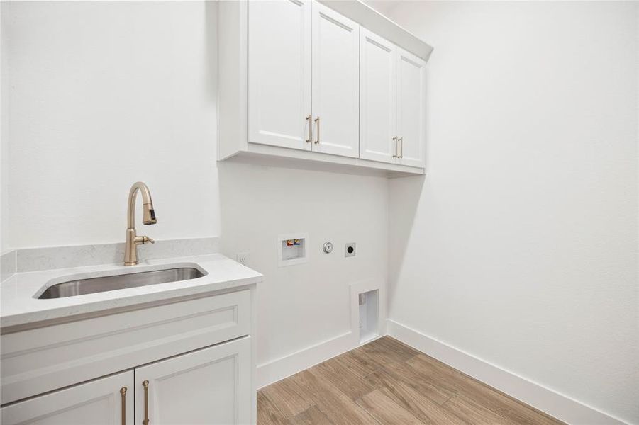 Laundry area with electric dryer hookup, cabinets, sink, washer hookup, and light wood-type flooring