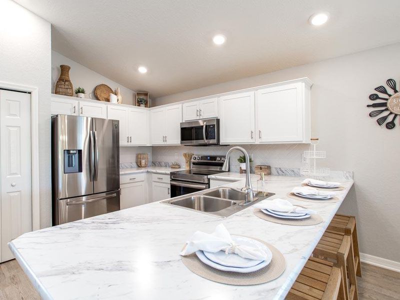 Sunny and open kitchen with pantry, counter-height bar, and your choice of finishes - Amaryllis home plan by Highland Homes