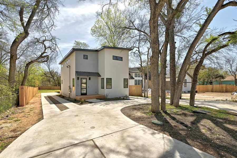 Modern home with stucco siding, curved driveway, and fence