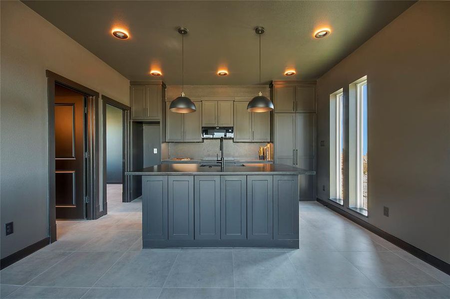 Kitchen featuring pendant lighting, backsplash, gray cabinets, a kitchen island with sink, and black microwave Kitchen featuring pendant lighting, backsplash, gray cabinets, a kitchen island with sink, and black microwave