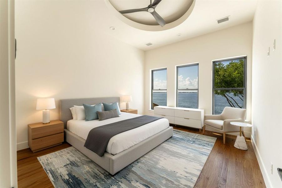 Bedroom with wood finished floors, a ceiling fan, and a water view