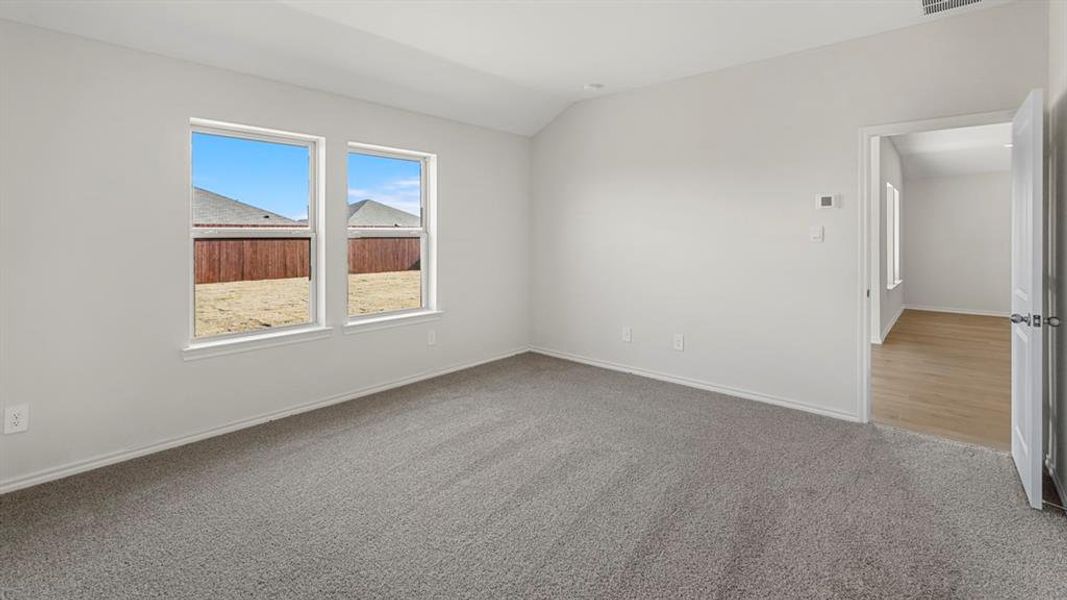 Bedroom featuring vaulted ceilings, neutral gray carpeting, and two large windows