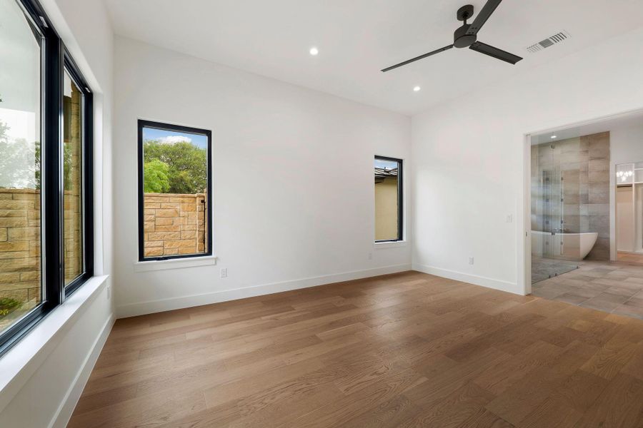 Spacious room featuring wood-finish flooring and multiple black-framed windows