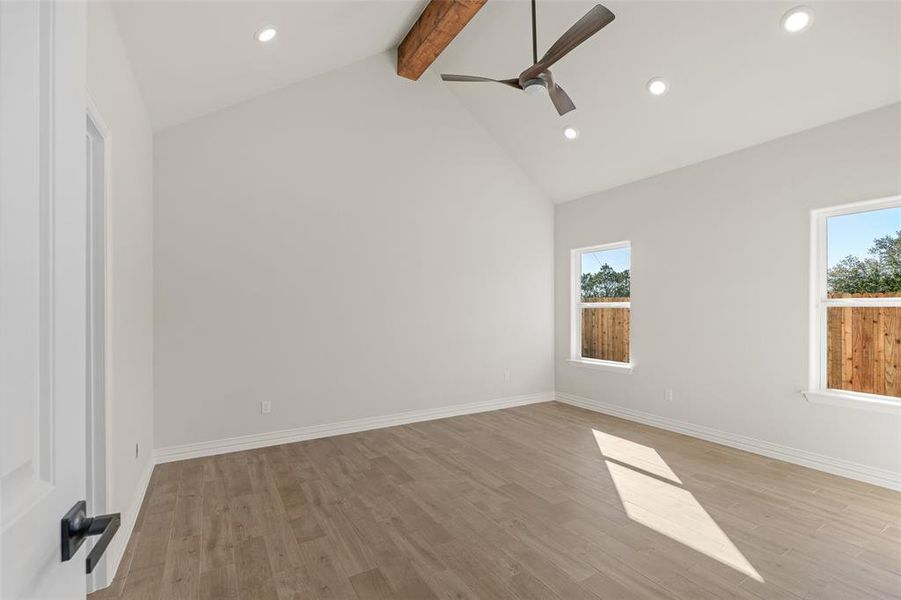 Unfurnished room with beamed ceiling, light hardwood / wood-style floors, high vaulted ceiling, and ceiling fan