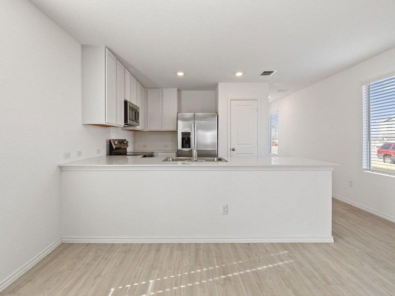 Kitchen featuring white cabinets, stainless steel appliances, a peninsula, light wood-style flooring, and recessed lighting