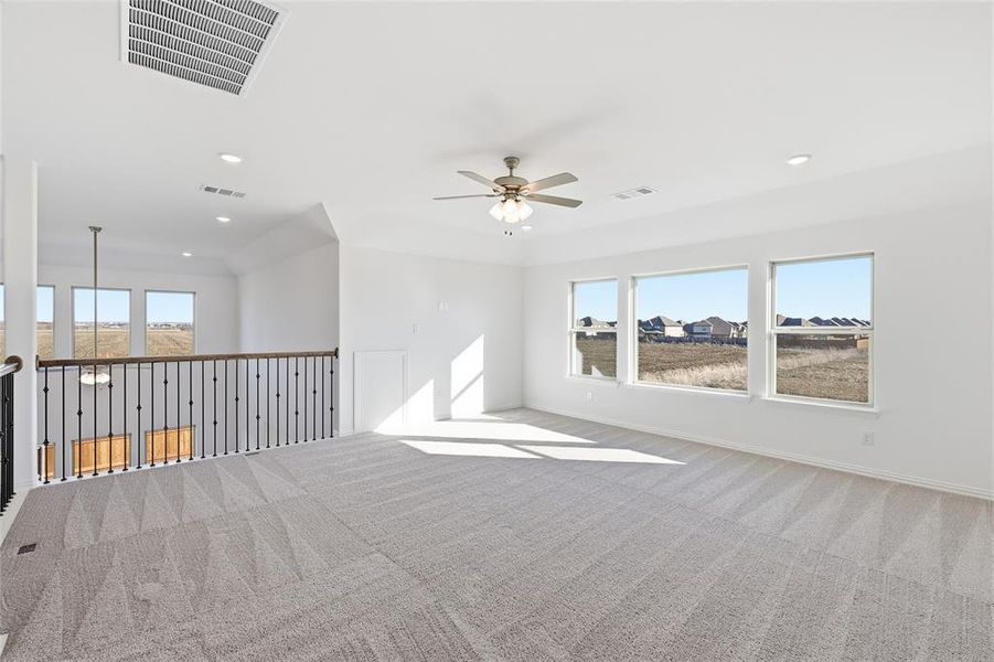 Spacious upstairs loft featuring light-toned carpet, multiple windows, recessed lighting, and a ceiling fan