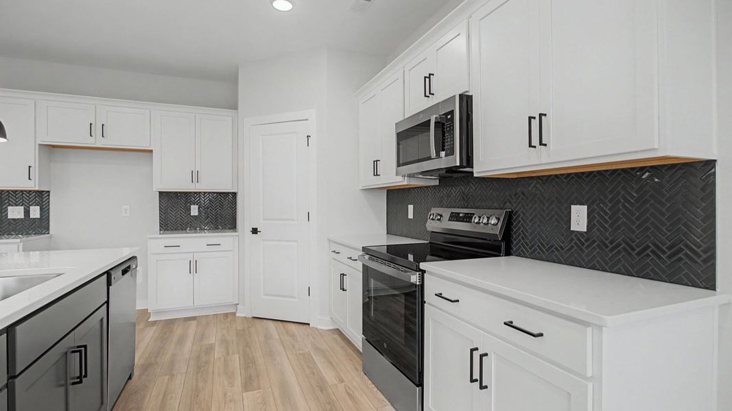 Kitchen with white cabinets and quartz countertops, tile accent backsplash, and pendant lighting