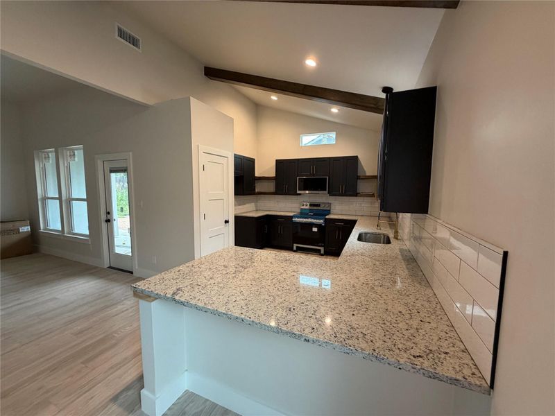 Culinary creations come to life in this kitchen featuring abundant granite counters and modern appliances.