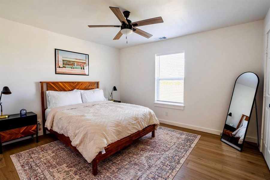 This room features light-toned walls, wood-look flooring, and a ceiling fan with integrated lighting