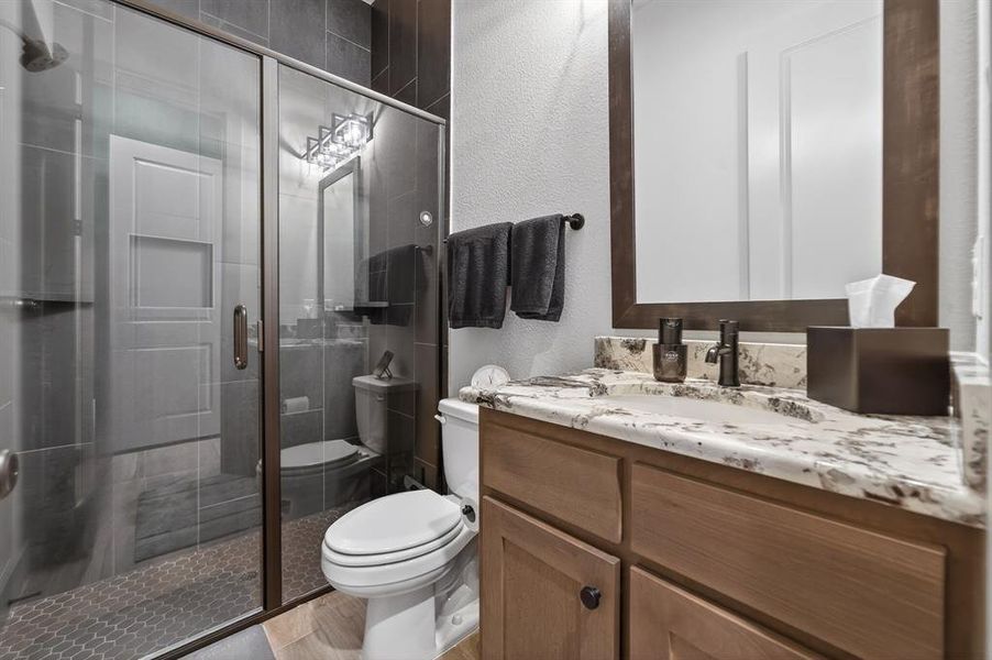 Full bathroom with a textured wall, vanity, and a shower stall Full bathroom with a textured wall, vanity, and a shower stall