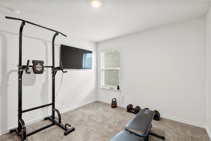 Exercise area with light carpet and baseboards