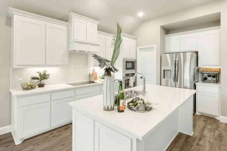 Kitchen with white cabinets, center island with sink, stainless steel appliances, and dark hardwood floors