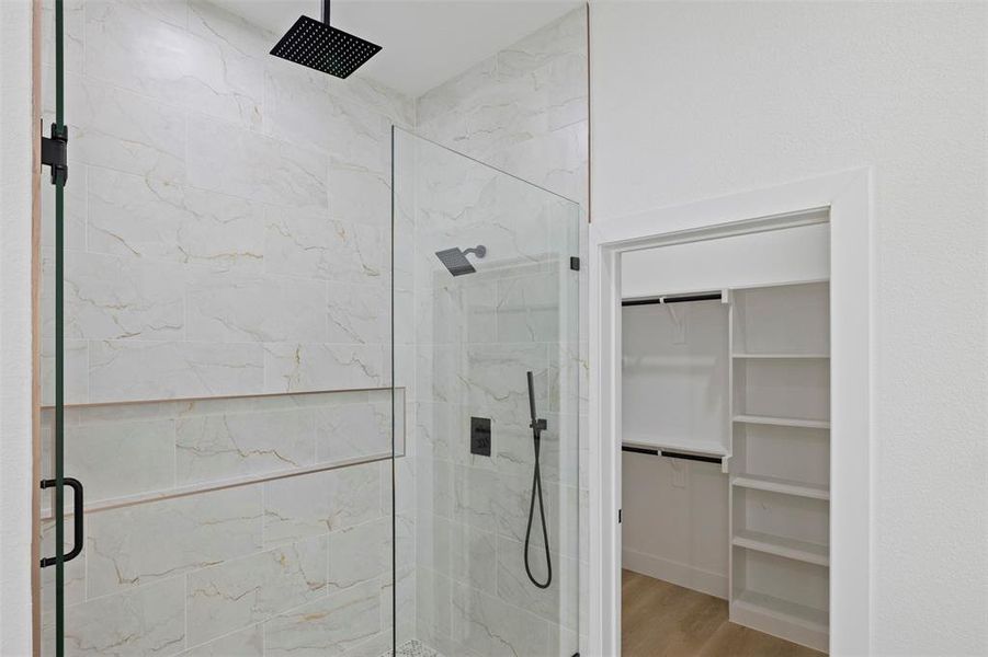 Full bathroom with a marble finish shower, a walk in closet, and light wood-type flooring