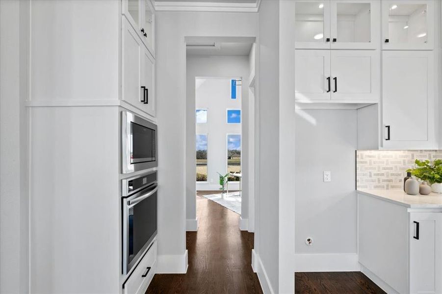 Kitchen with white cabinetry, stainless steel appliances, dark wood-type flooring, and tasteful backsplash