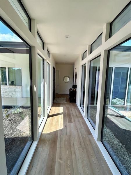 Hallway with light wood-style floors and expansive windows Hallway with light wood-style floors and expansive windows