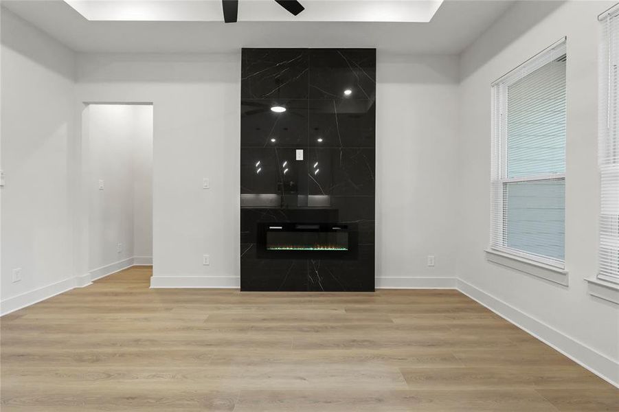 Unfurnished living room with wood finished floors, a high end fireplace, and ceiling fan