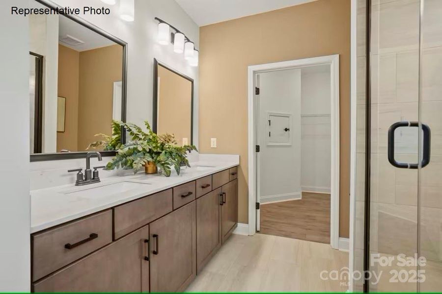 Primary bathroom with dual vanities and walk-in shower with tiled bench seat