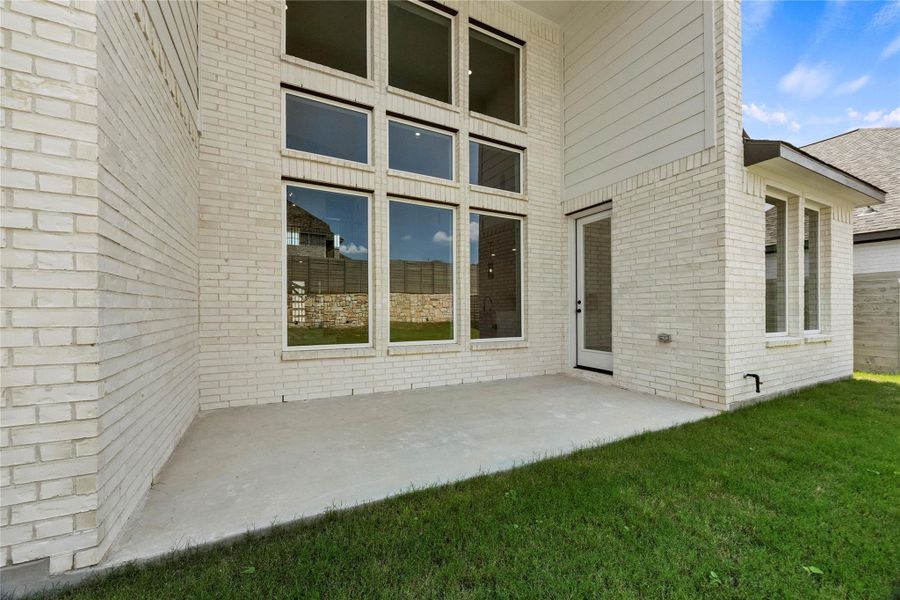 Doorway to property with brick siding, a patio, and a yard