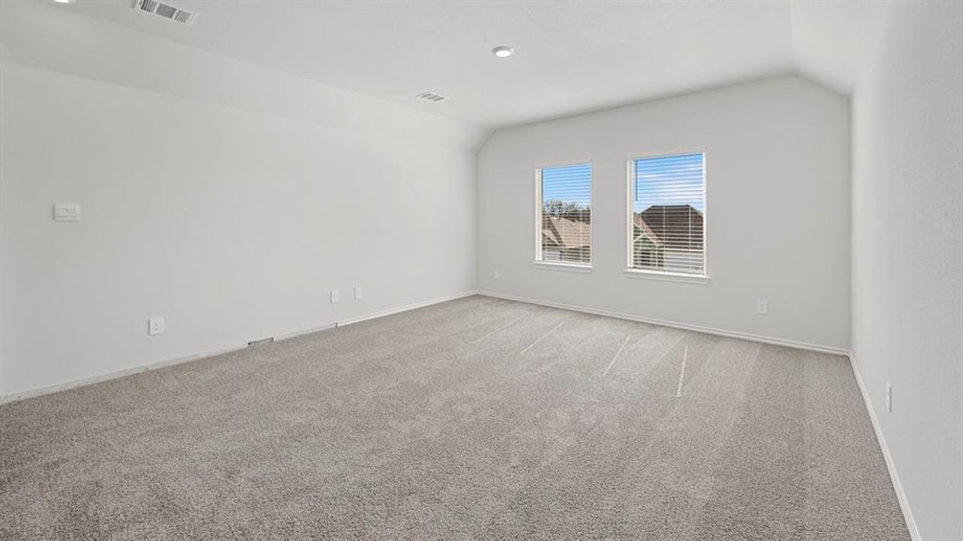 Spare room featuring light carpet and lofted ceiling