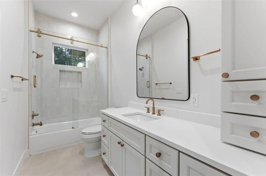 Full bath with enclosed tub / shower combo, vanity, and light tile patterned floors