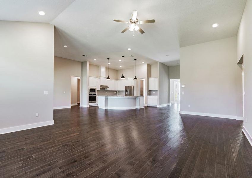 Living room with wood floors and fan overlooking the dining room and kitchen.