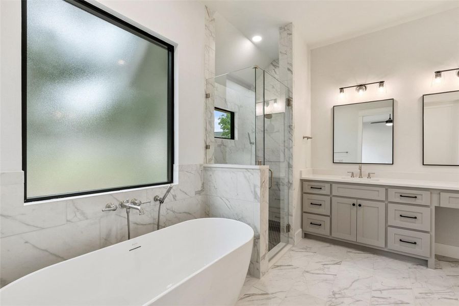 A well-lit primary bathroom features a standalone soaking tub and a spacious, glass-enclosed shower.